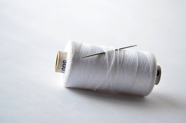 spool of white thread and a needle